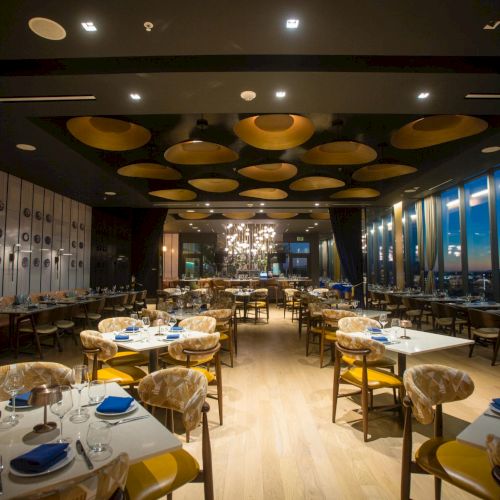 A cozy cafe or lounge with warm lighting, wooden tables, and people seated around, possibly enjoying a casual meal or drinks.