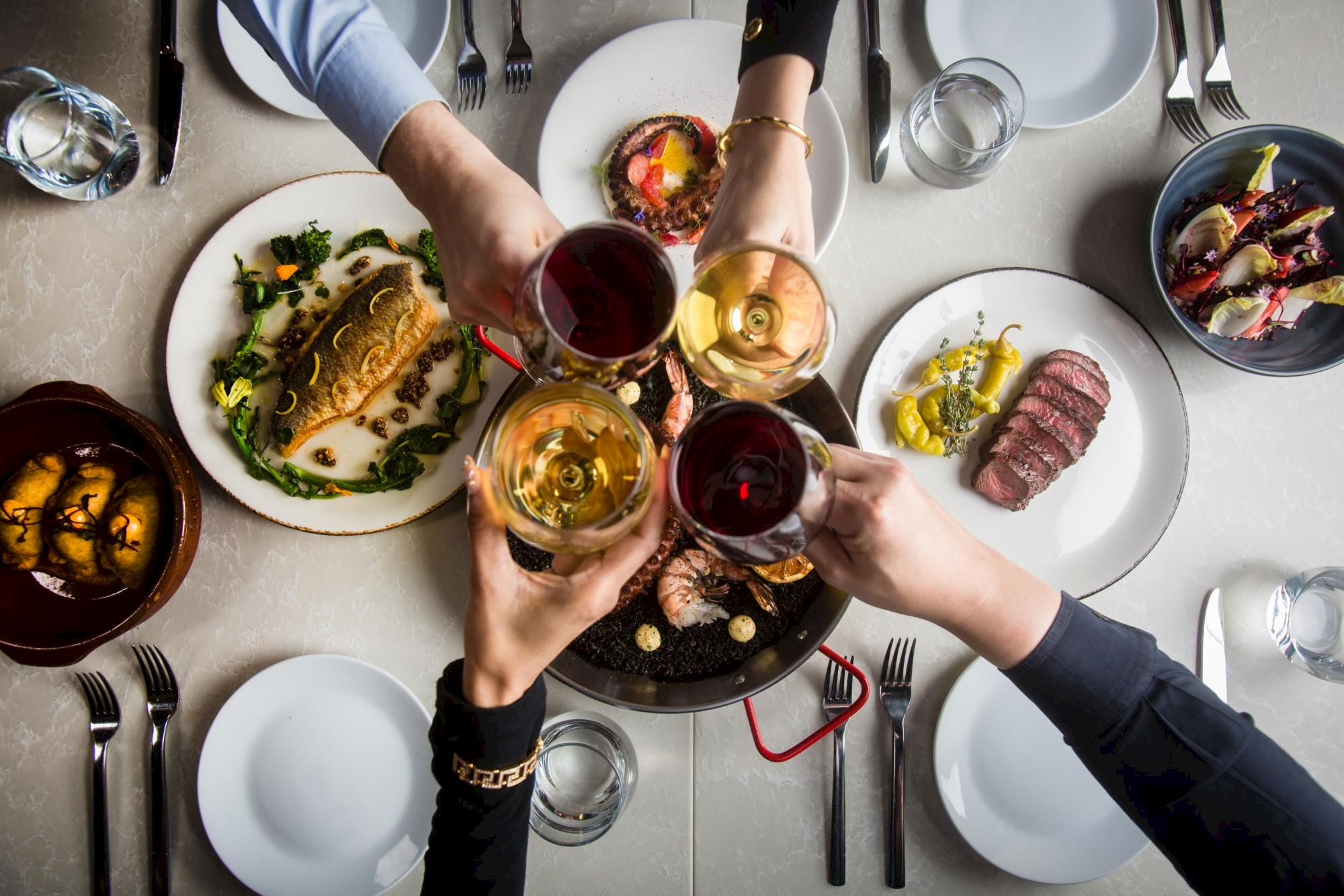 A group of people toasting with drinks over a shared meal at a table.